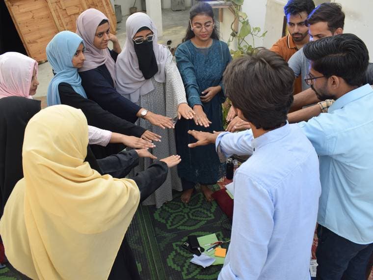 Attendees standing in a close circle with their hands together at Session 2