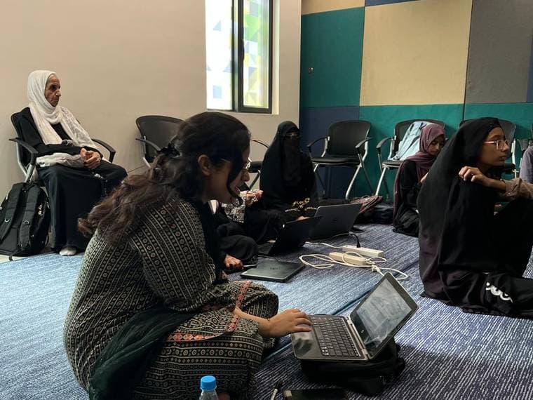 Two attendees working at laptops in a quieter corner during Session 4