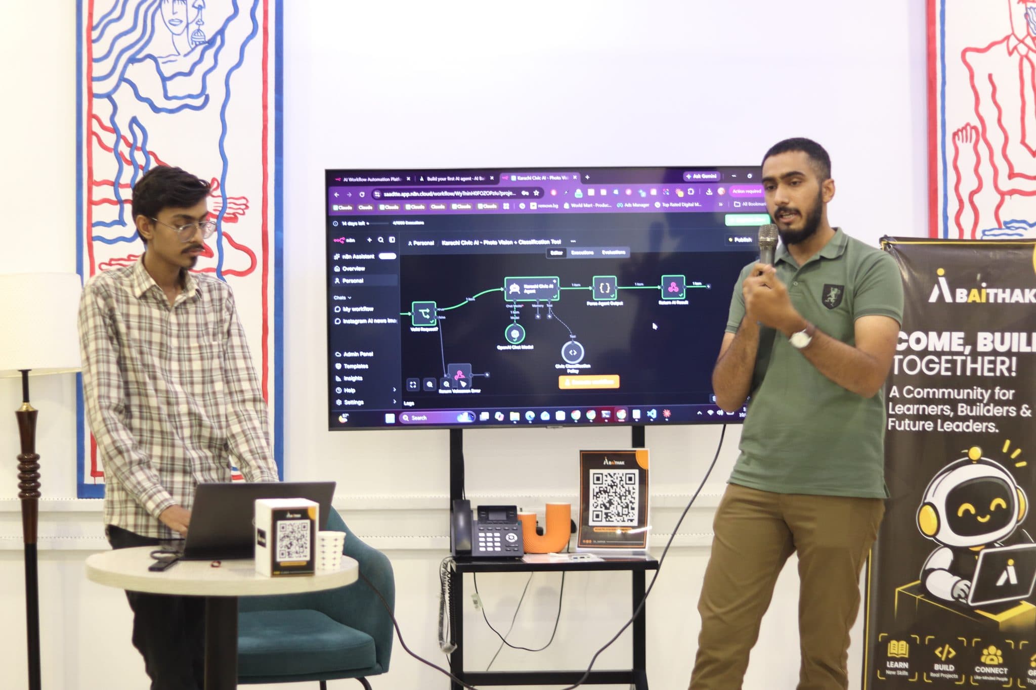 Two speakers at the front at Session 7, one at a laptop and one with a microphone beside a screen showing an agent's workflow