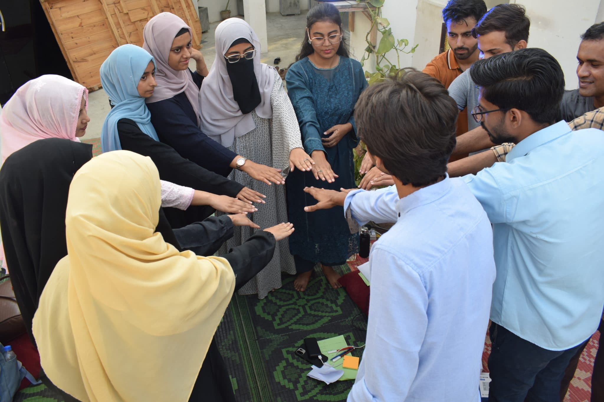Attendees standing in a close circle with their hands together at Session 2