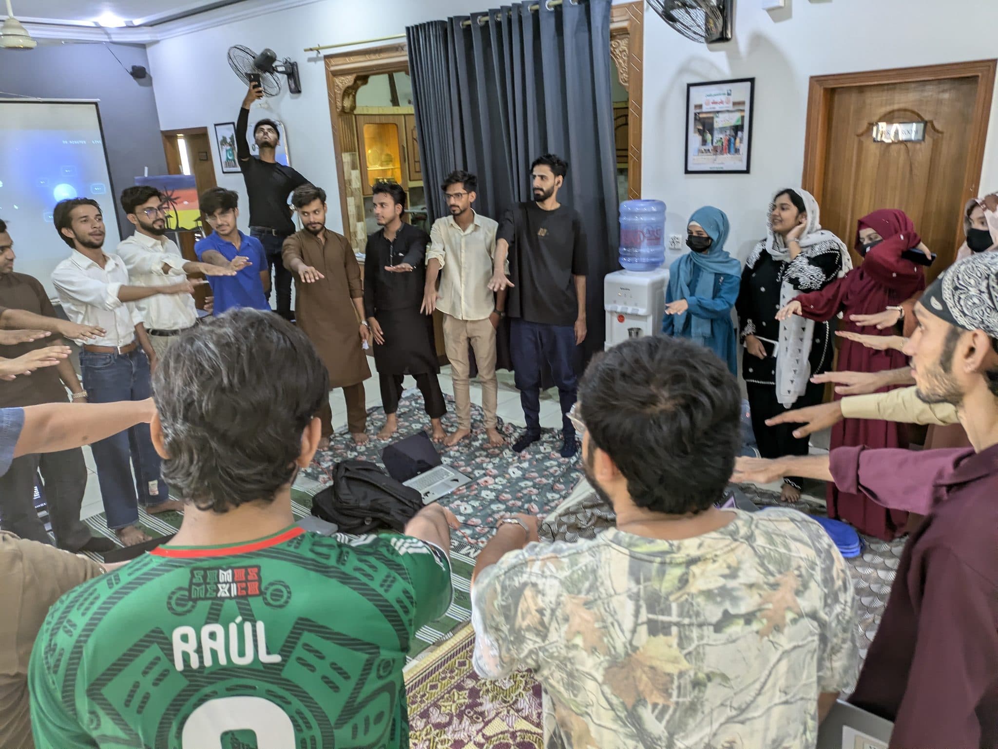 Attendees standing in a circle with hands raised at the end of Session 3
