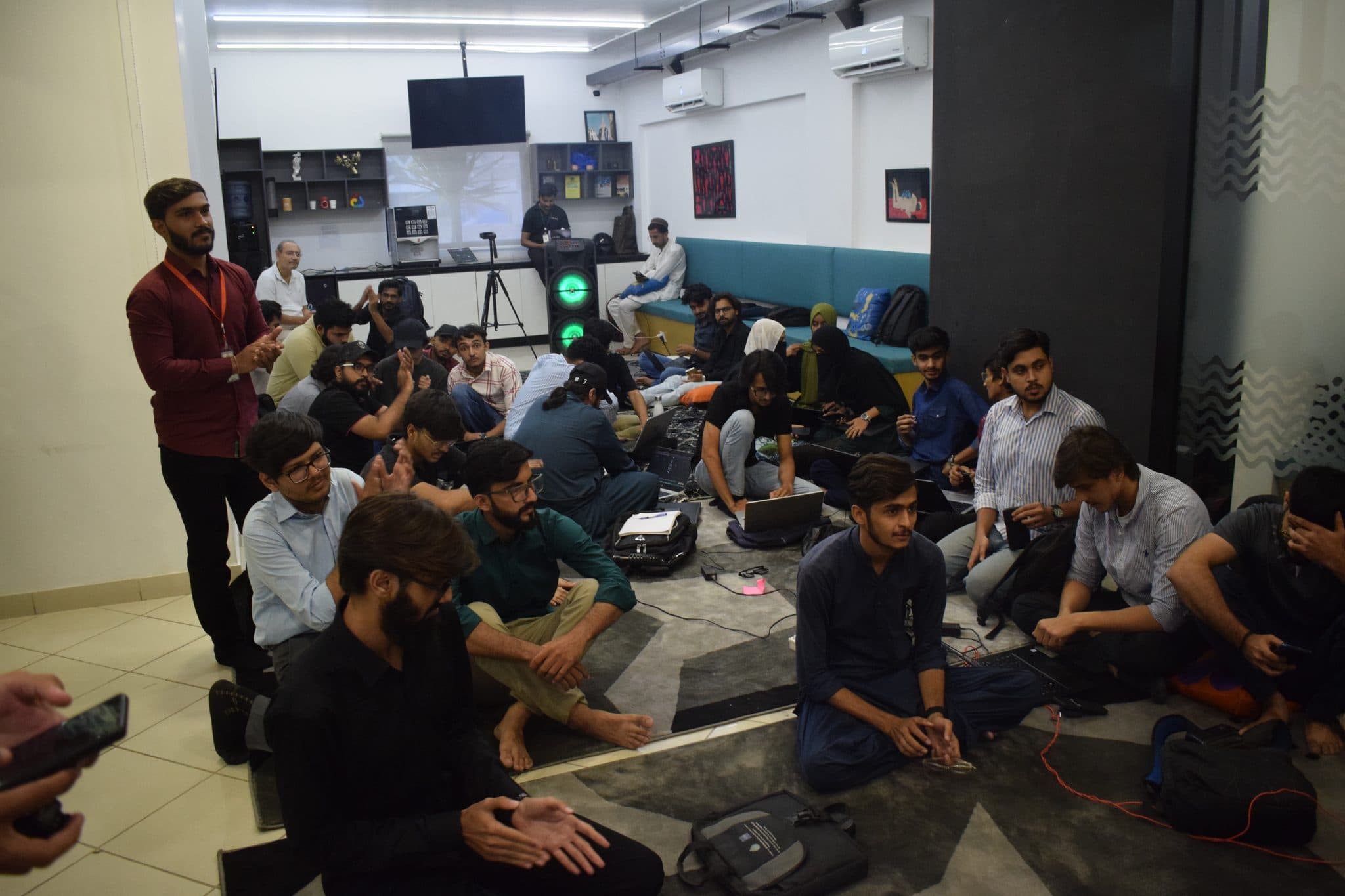 A packed room seated on the floor at Session 5