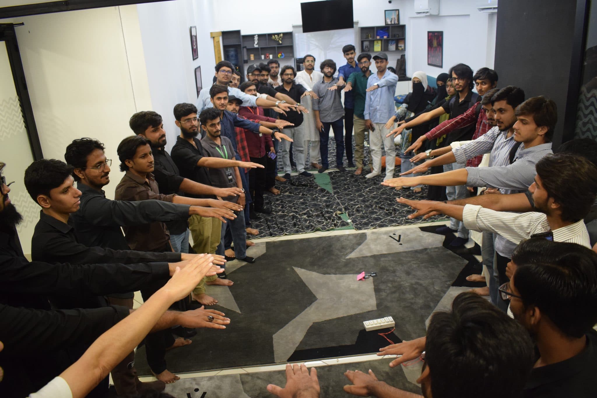 A wide circle of attendees reaching into the middle at Session 5